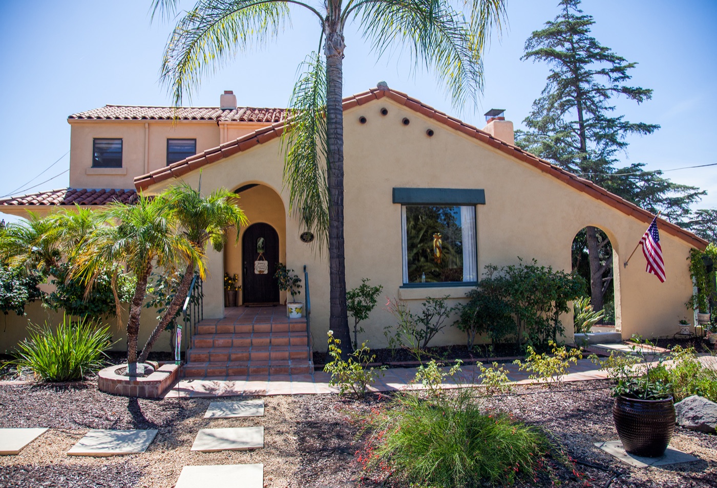 Spanish-style historic home exterior with red tile roof and garden