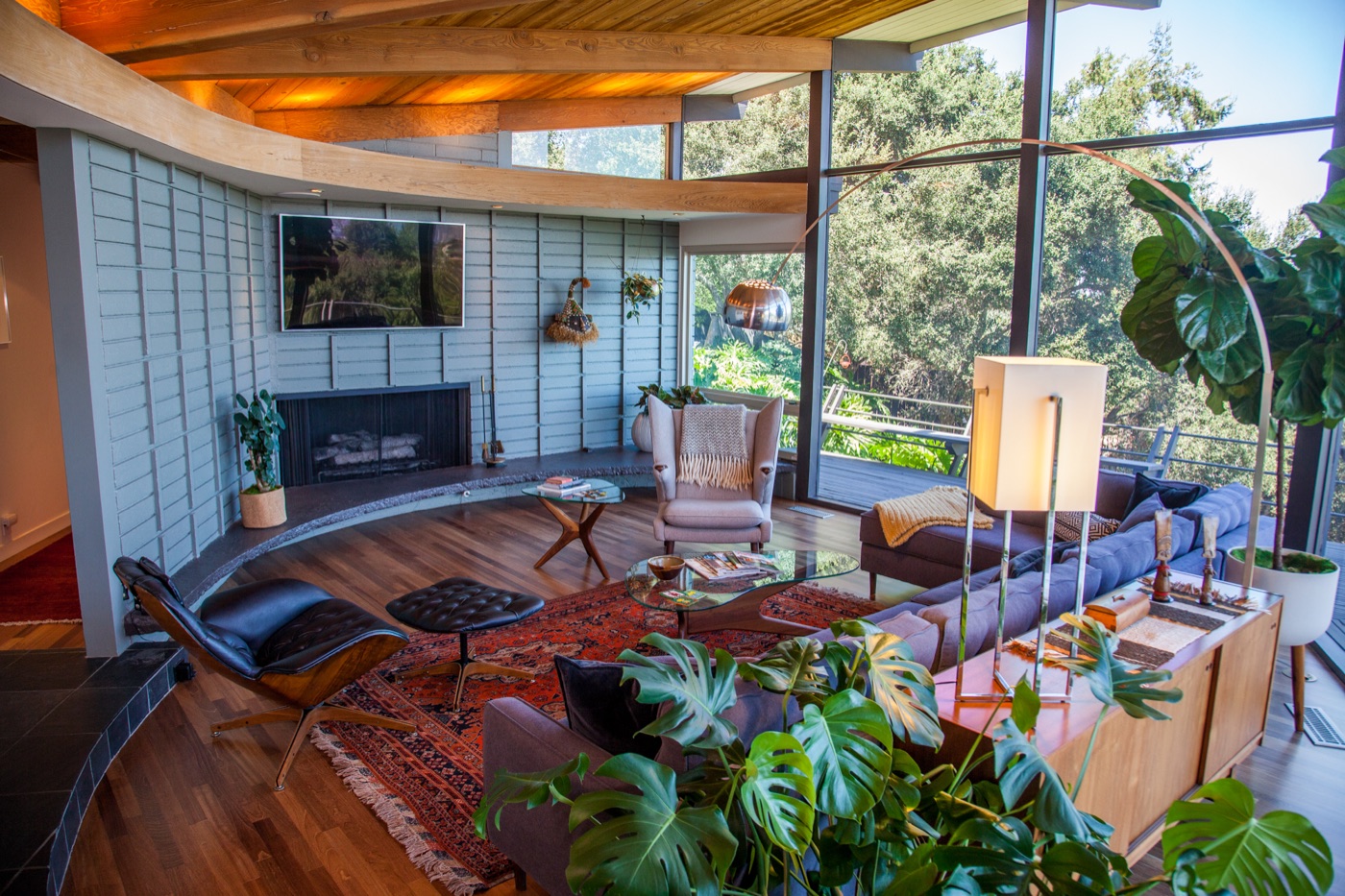 Mid-century home interior with vaulted wood ceiling, fireplace, and large windows